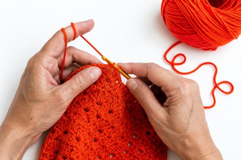 Manos tejiendo a crochet con hilo rojo