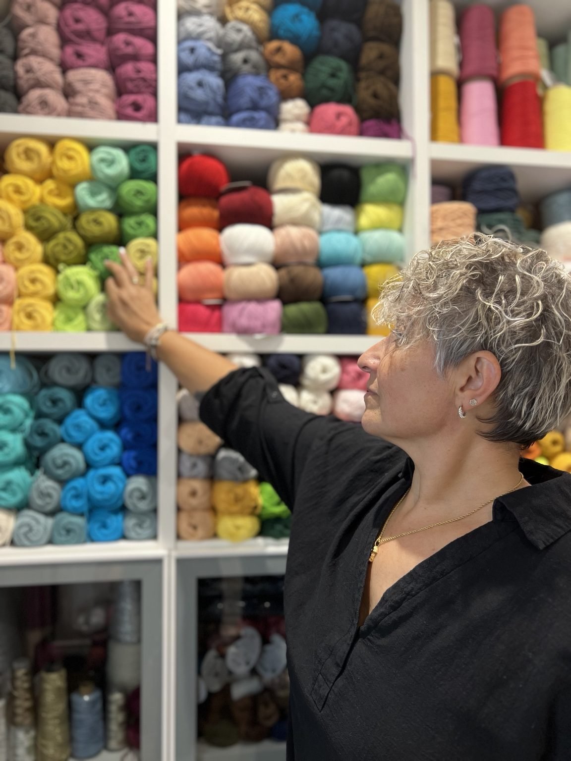 Isa junto a una estantería de ovillos de colores