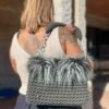 Bolso de crochet verde botella con pelo sintético y asa de cadena plateada, llevado al hombro