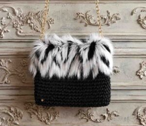 Bolso de crochet negro con pelo sintético blanco y negro y cadena dorada