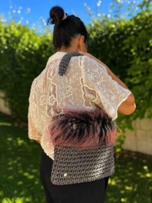 Bolso de crochet gris con pelo negro, gris y rosa, llevado al hombro