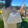 Bolso de crochet beige con asa de eslabones verde oliva llevado al hombro