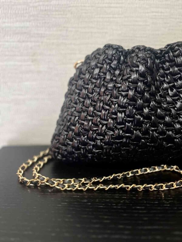 Detalle del bolso de efecto cuero trenzado negro y su cadena dorada