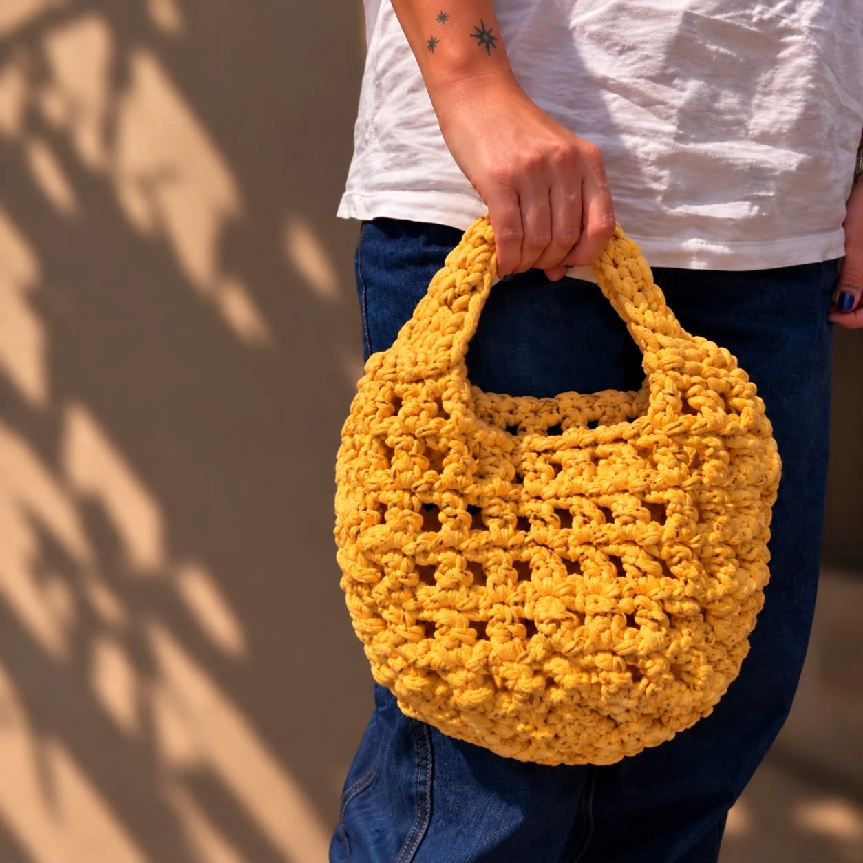 Bolso de crochet amarillo hecho a mano, sujeto por el asa
