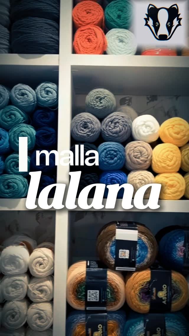 Estanterías de ovillos del estudio de malla-lalana con el escudo del tejón de la peña Teixugos Celestes